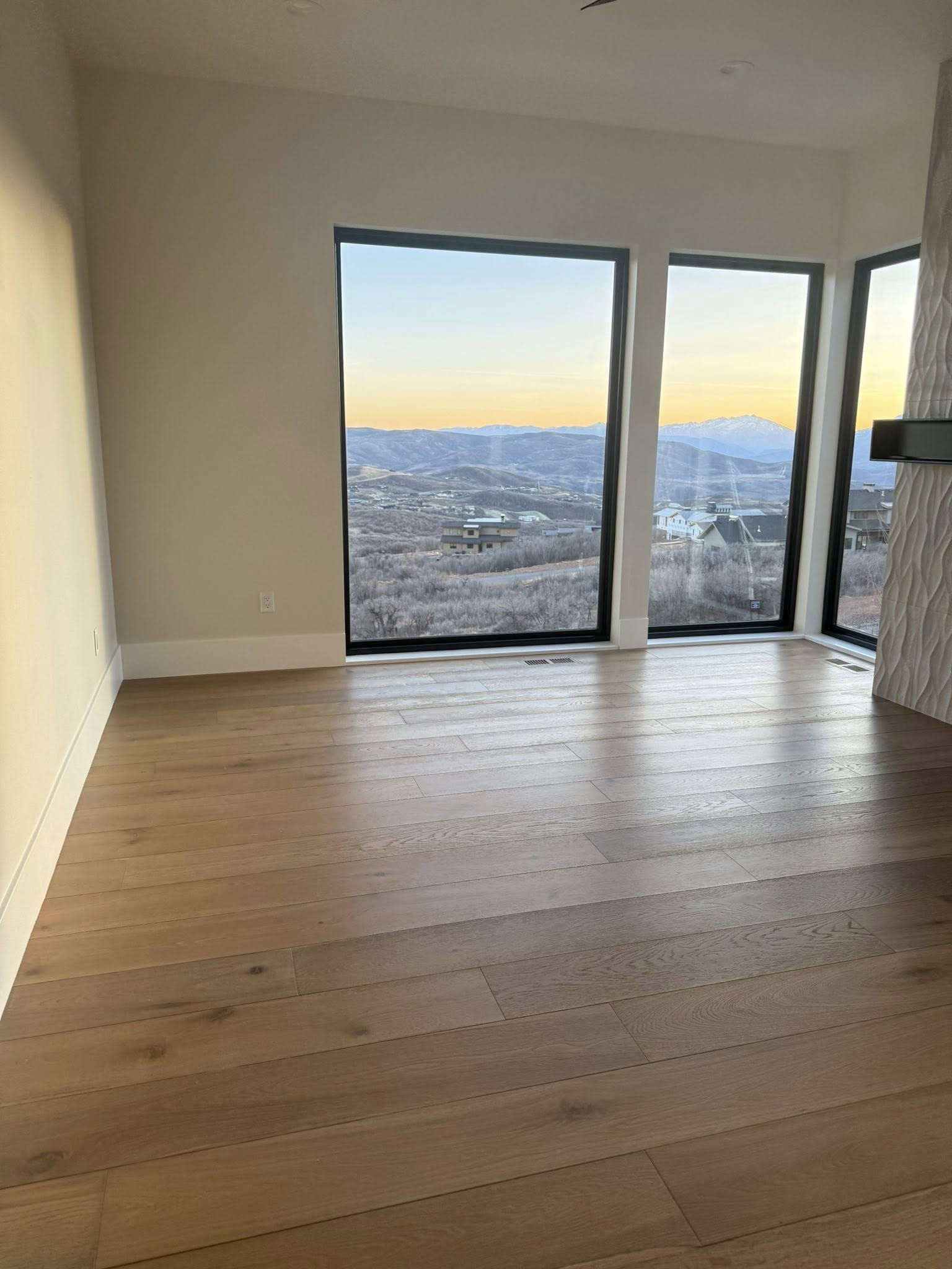 Empty living room with pristine hardwood floors and mountain view after move-out clean